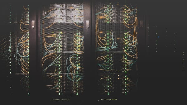 Dark server rack with fiber optic cables and glowing LED connections